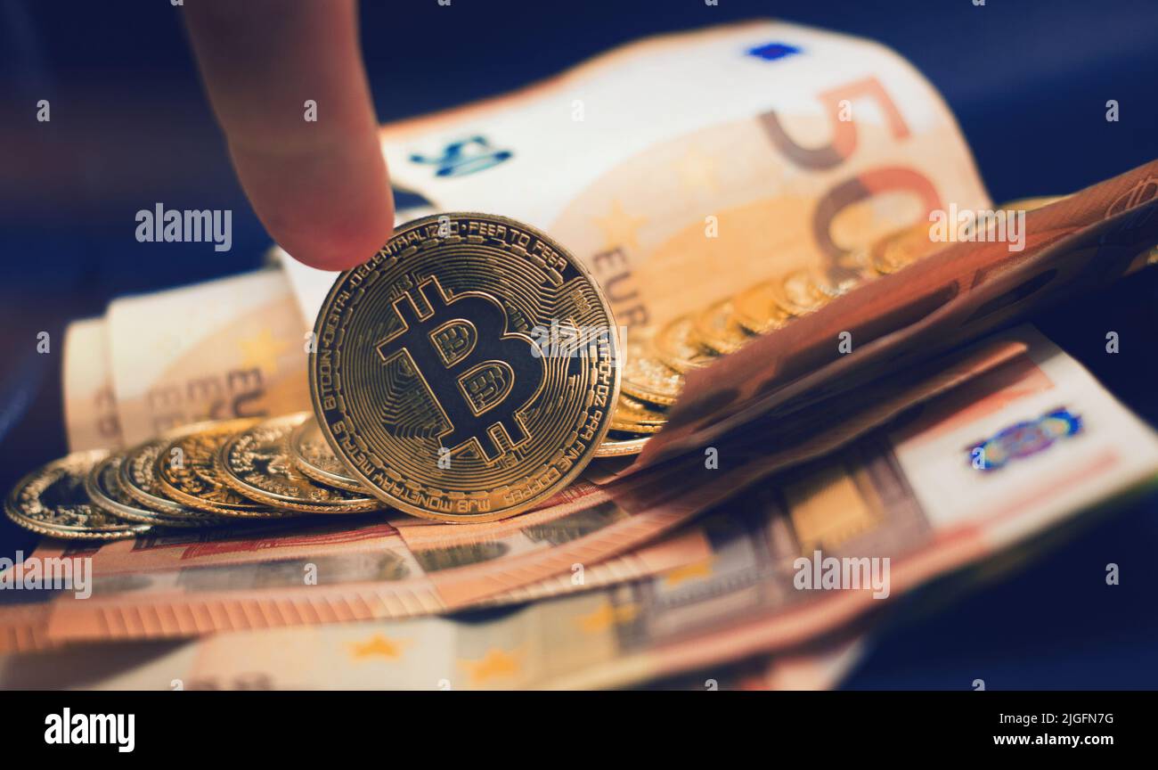 Handrollen einer Bitcoin mit einem Stapel von Münzen mit europäischen Banknoten als Hintergrund . Konzept der Kryptowährung . Stockfoto