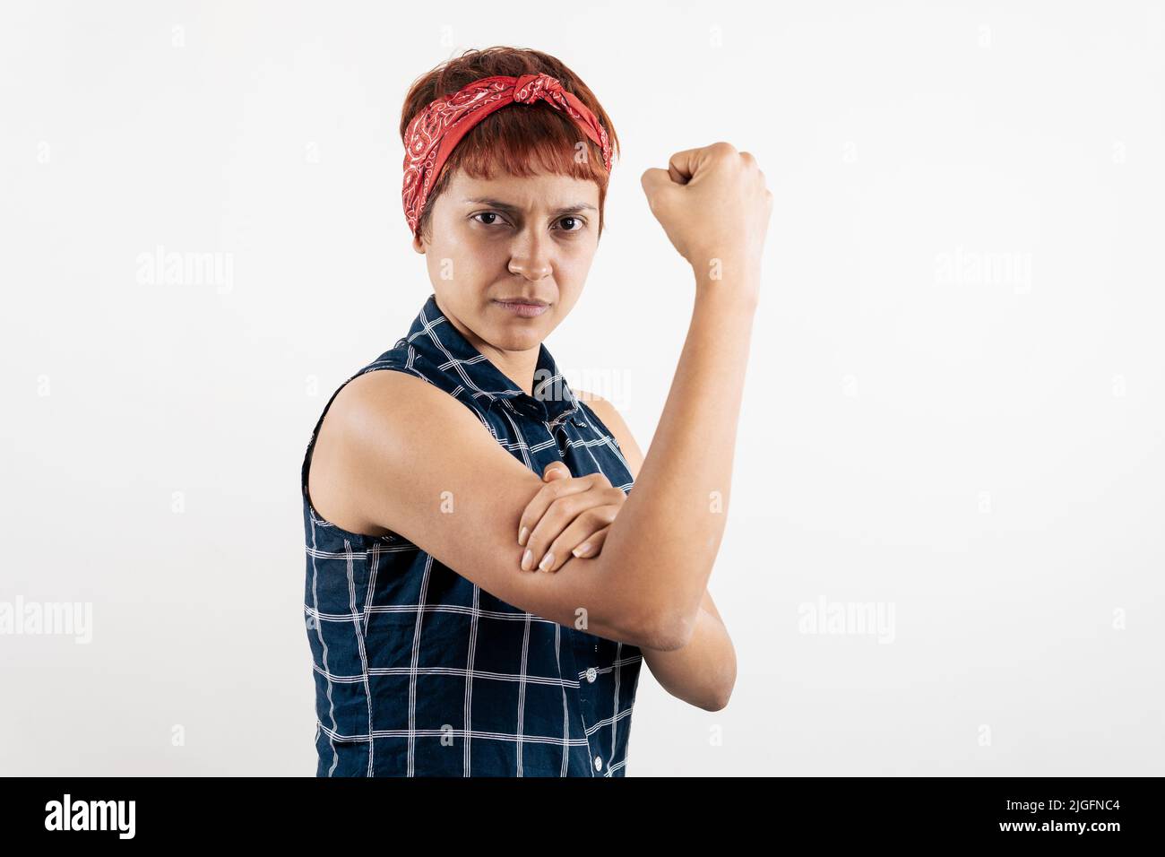 Eine lateinische Frau mittleren Alters imitiert die Pose von Rosie, dem Riveter Stockfoto