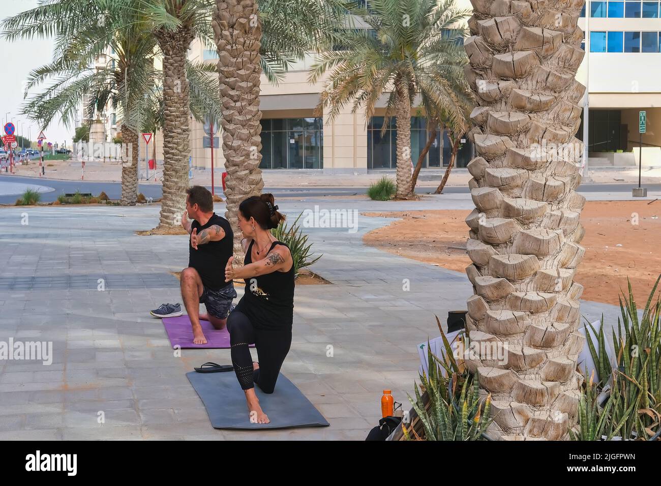 Paar machen Yoga-Übungen in der Stadt Straße. Reife sportliche Frau und Mann üben gemeinsam im Freien Yoga-Action-Übung Stockfoto