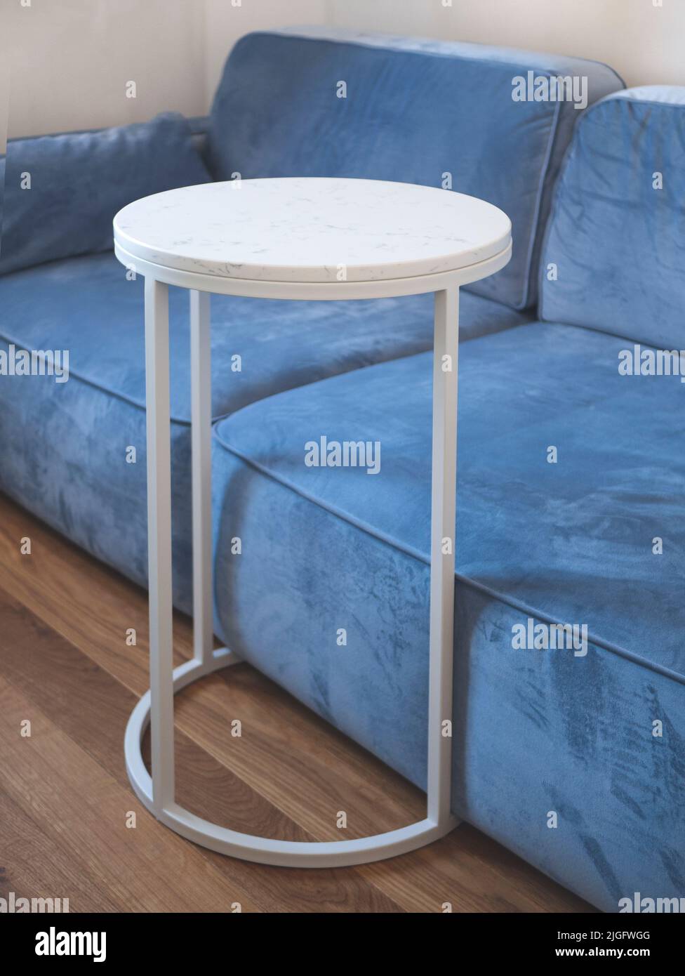 Runder Couchtisch mit Metallrahmen und weißer Marmorplatte in einem Sitzbereich, selektiver Fokus. Beistelltisch für kleine Räume. Praktisch und Platz-s Stockfoto