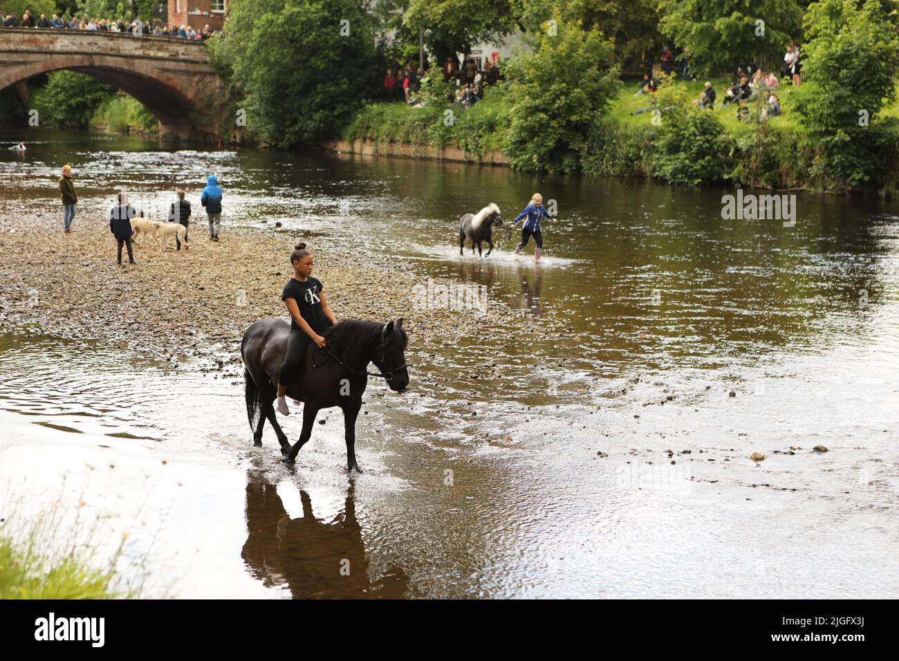 Ein Teenager-Mädchen, das auf ihrem Pferd im Fluss Eden, auf der Appleby Horse Fair und auf der Appleby in Westmorland, Cumbria, reitet Stockfoto