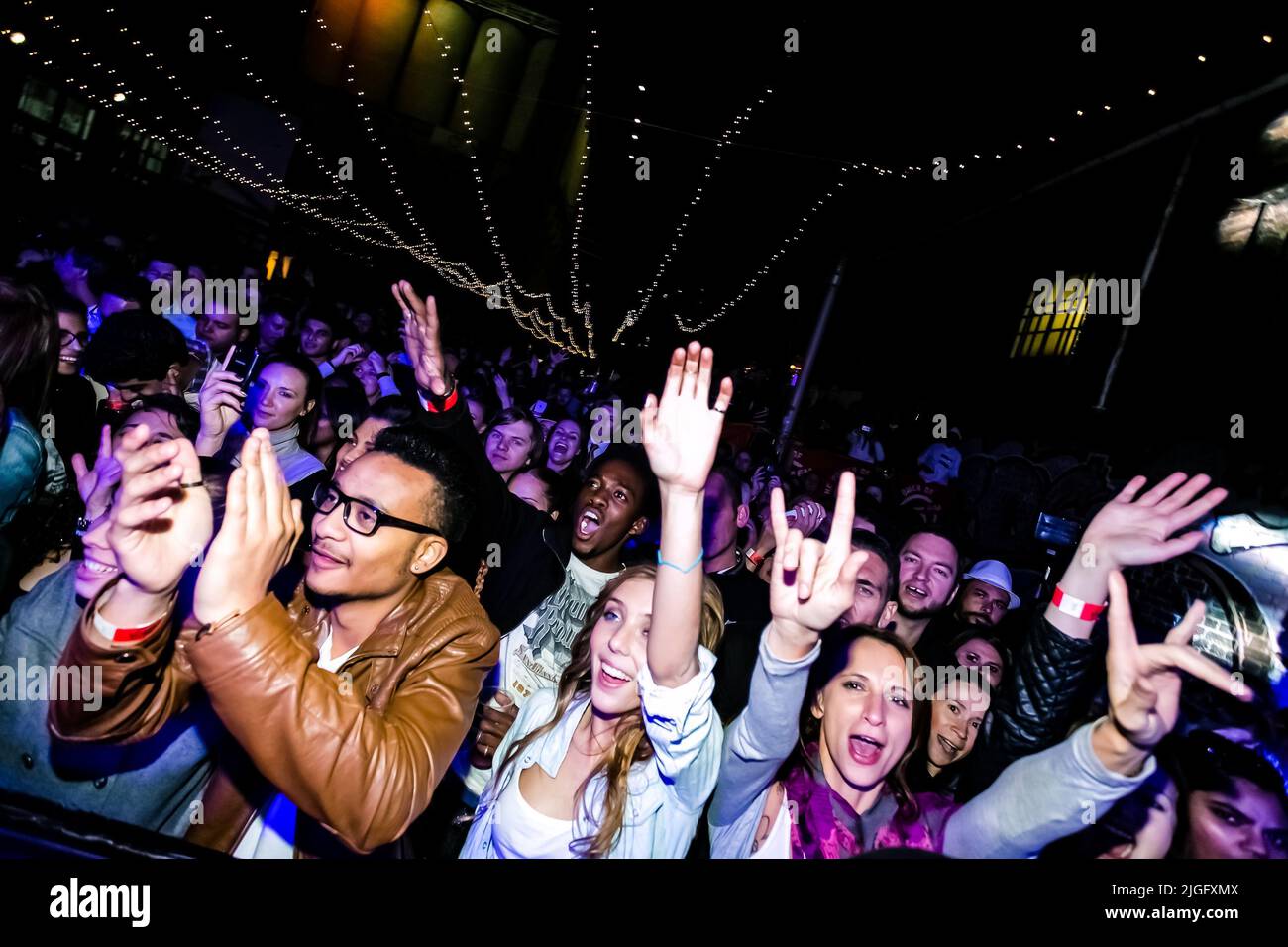 Eine Gruppe von trendigen jungen Leuten, die bei einem Musikkonzert dabei sind und Spaß haben Stockfoto