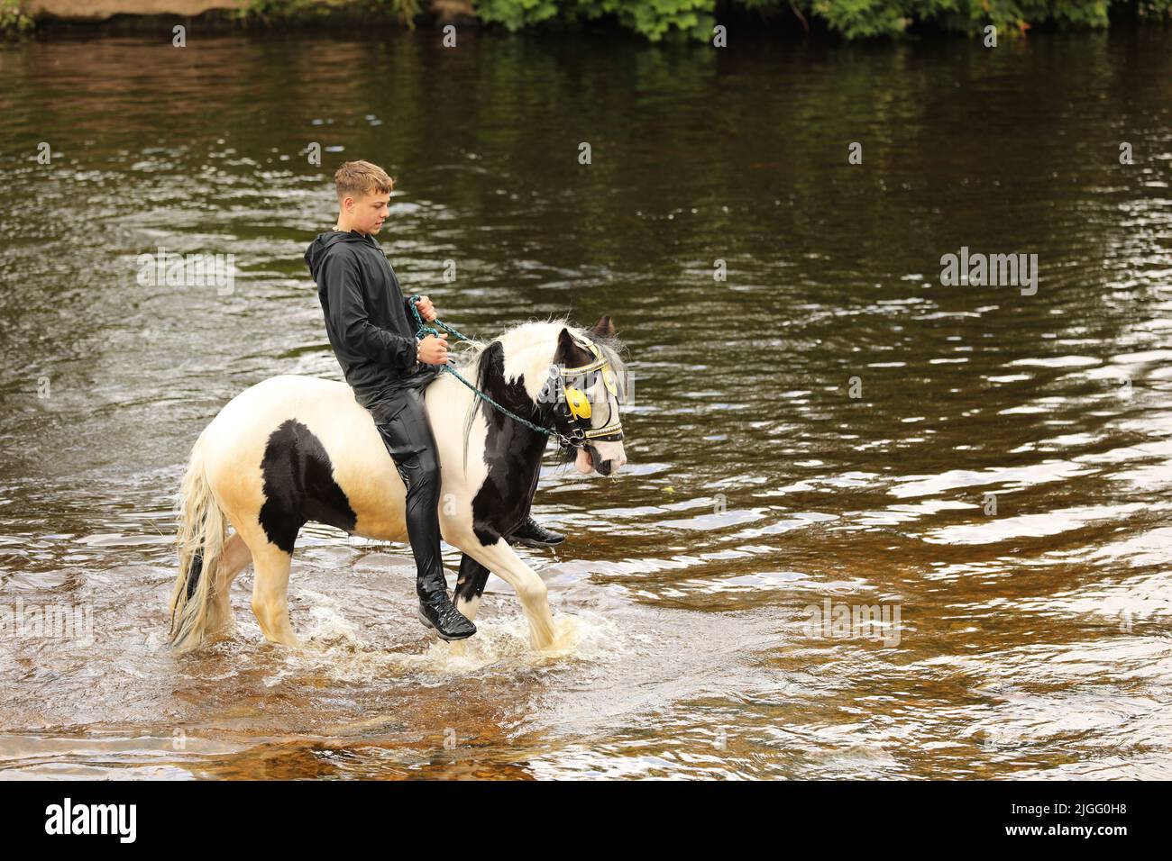 Ein Teenager, der auf seinem Pferd im Fluss Eden, auf der Appleby Horse Fair und auf der Appleby in Westmorland, Cumbria, reitet Stockfoto