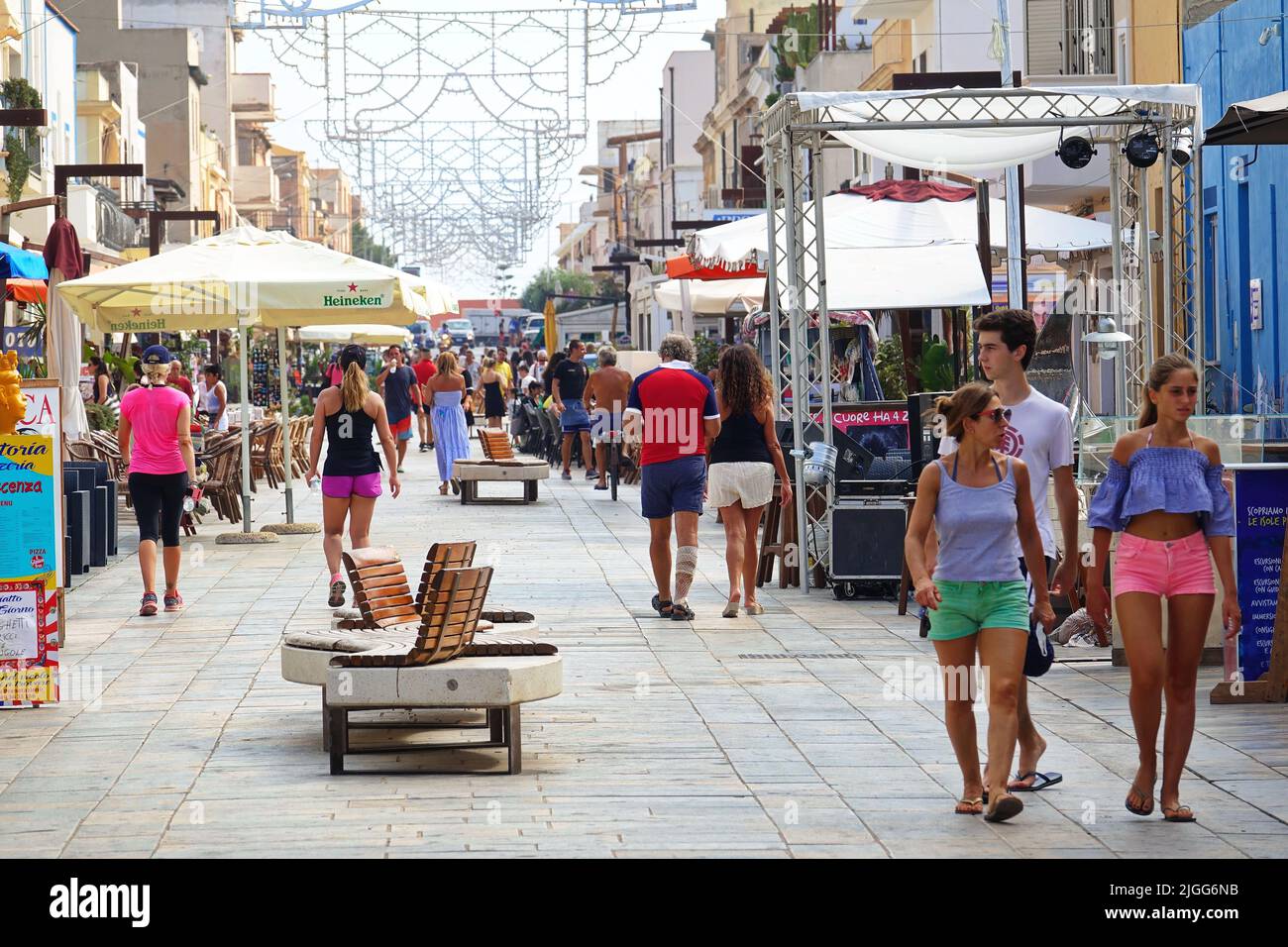 Touristen, die die Hauptstraße entlang laufen, in der es zahlreiche Bars, Geschäfte und andere wichtige Aktivitäten gibt. LAMPEDUSA, ITALIEN - AUGUST 2019 Stockfoto