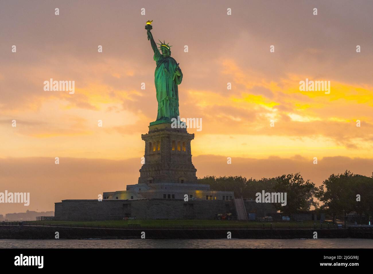 Freiheitsstatue, New York, USA, während der goldenen Stunde mit einem bewölkten Himmel im Hintergrund Stockfoto