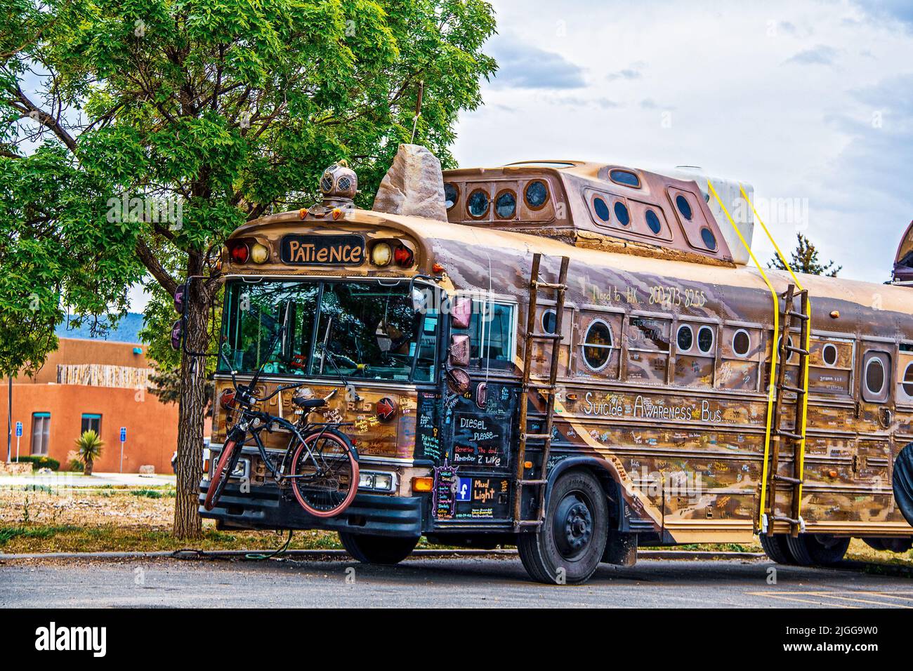 2021 05 21 Taos NM USA Steampunk umgebauter Kunstbus für Reise- und Selbstmordbewusstsein mit Unterschriften auf dem ganzen Bus und Fahrrad vorne befestigt Stockfoto