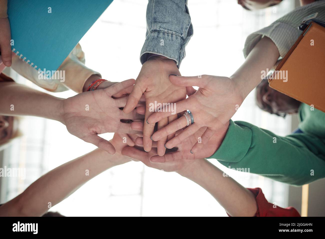 Unter dem Winkel des Stapels von Händen einer Gruppe von Jugendlichen Studenten in der Kasualwear als Symbol für Teamarbeit, Unterstützung, Freundschaft und Einheit Stockfoto