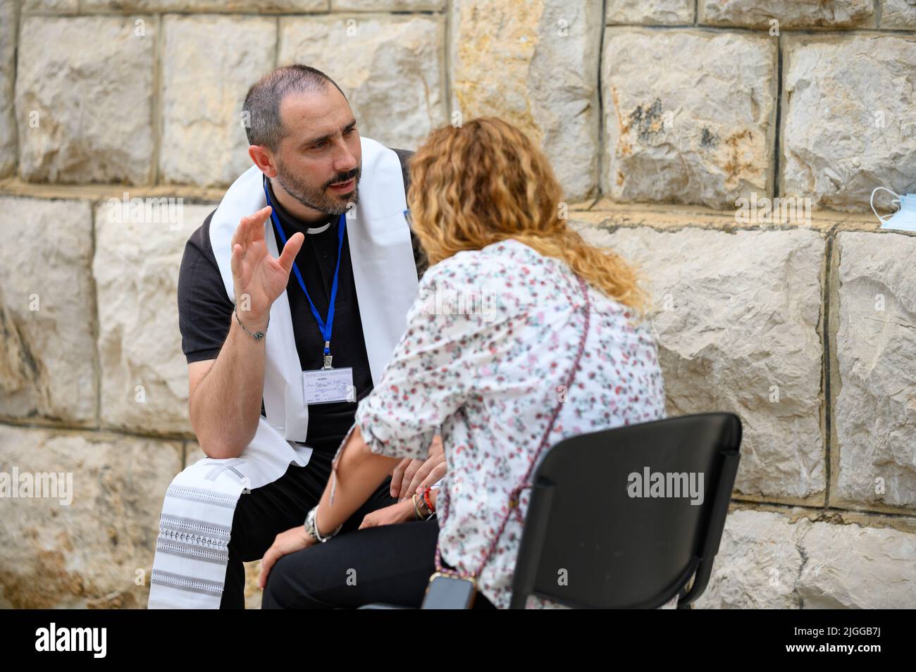Katholische Beichte – eine Frau, die einem katholischen Priester beichtet – während des Mladifest 2021, dem Jugendfestival in Medjugorje. Stockfoto