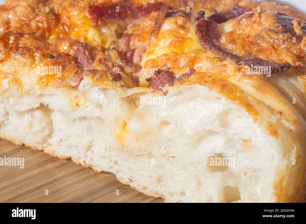 Frisch gebackene italienische Foccacia mit gelbem Käse und Pastrami, in einer Holztafel mit Kopieplatz. Stockfoto