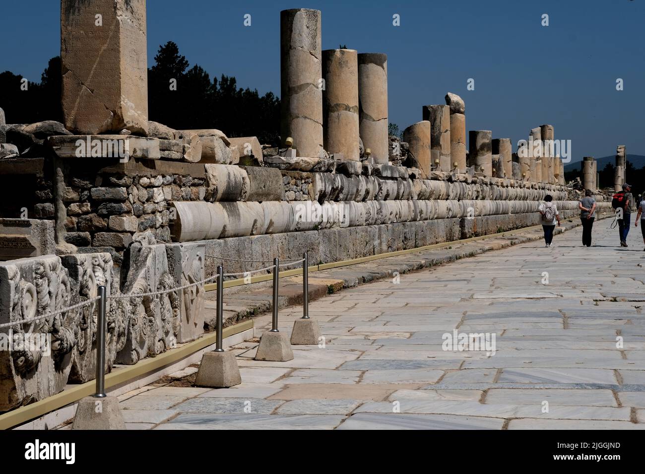 Touristen gehen in der einst großartigen Stadt Ephesus in der Türkei eine Straße entlang Stockfoto