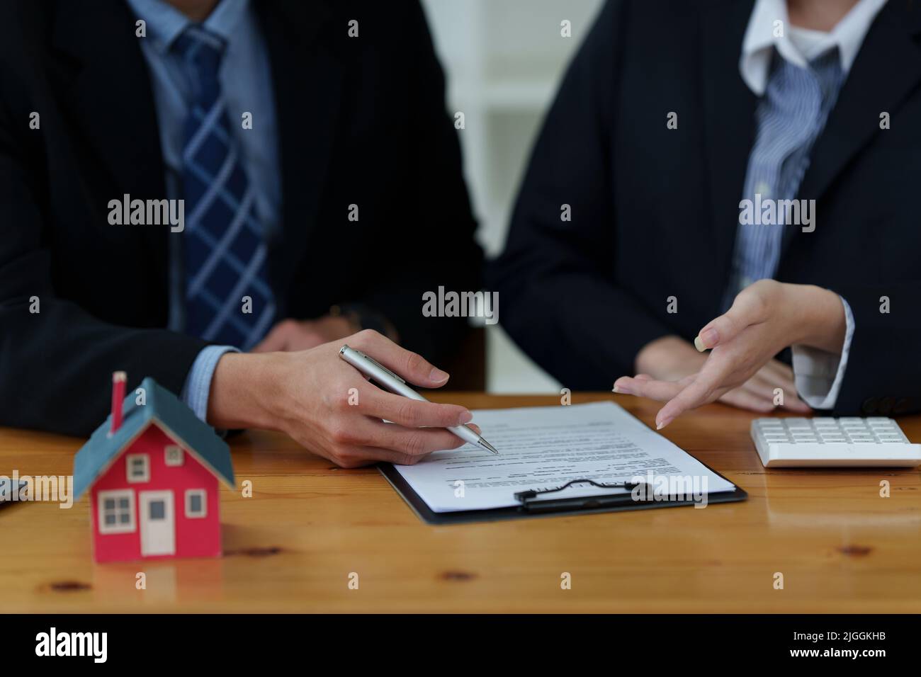 Nahaufnahme des Geschäftsmanns, der auf den Kauf eines Hauses hinweist und eine Vereinbarung unterzeichnet. Bankmanager und Immobilienkonzept. Stockfoto