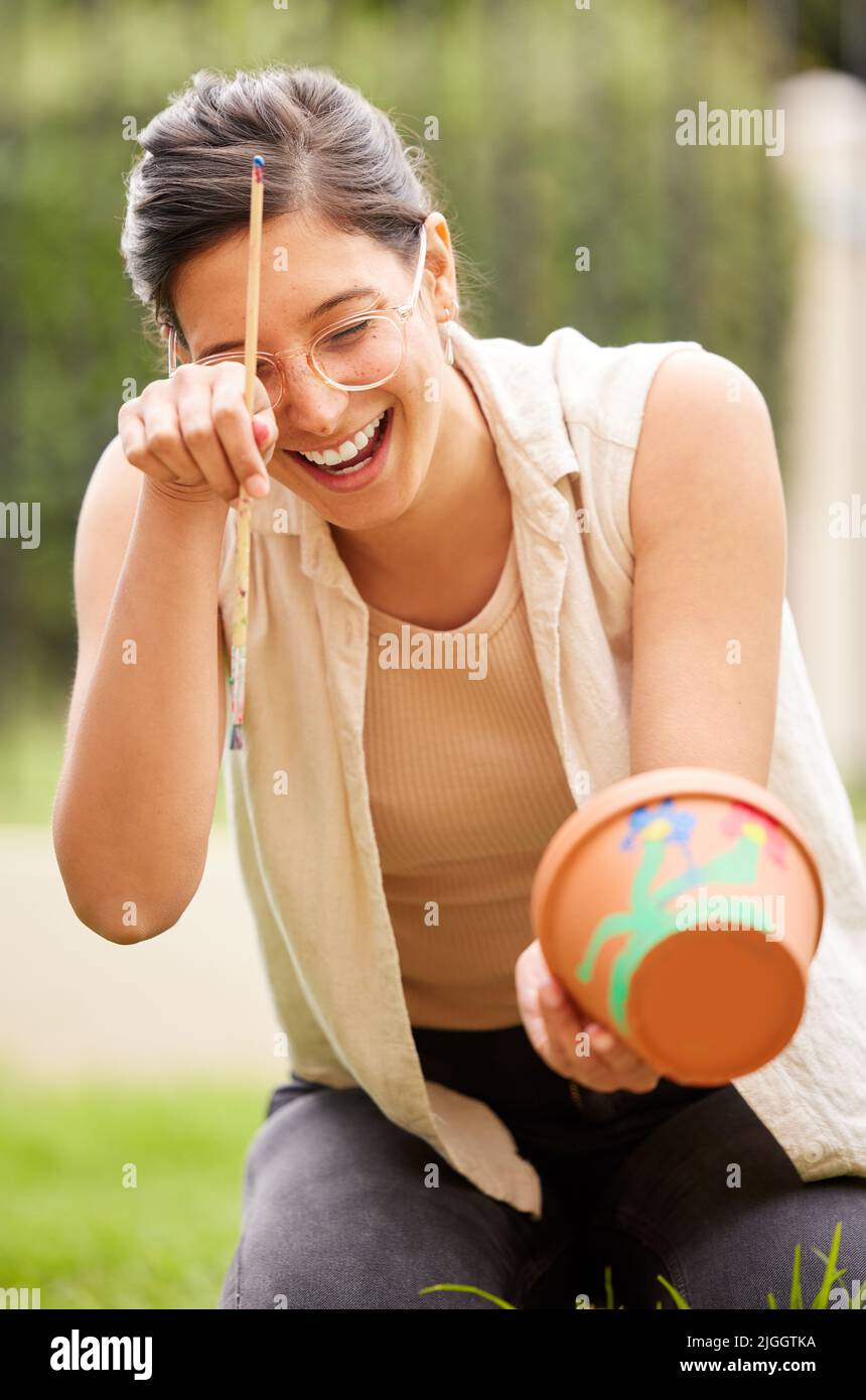 Es besteht kein Zweifel, dass Kreativität die wichtigste menschliche Ressource von allen ist. S junge Frau malen einen Topf im Garten zu Hause. Stockfoto