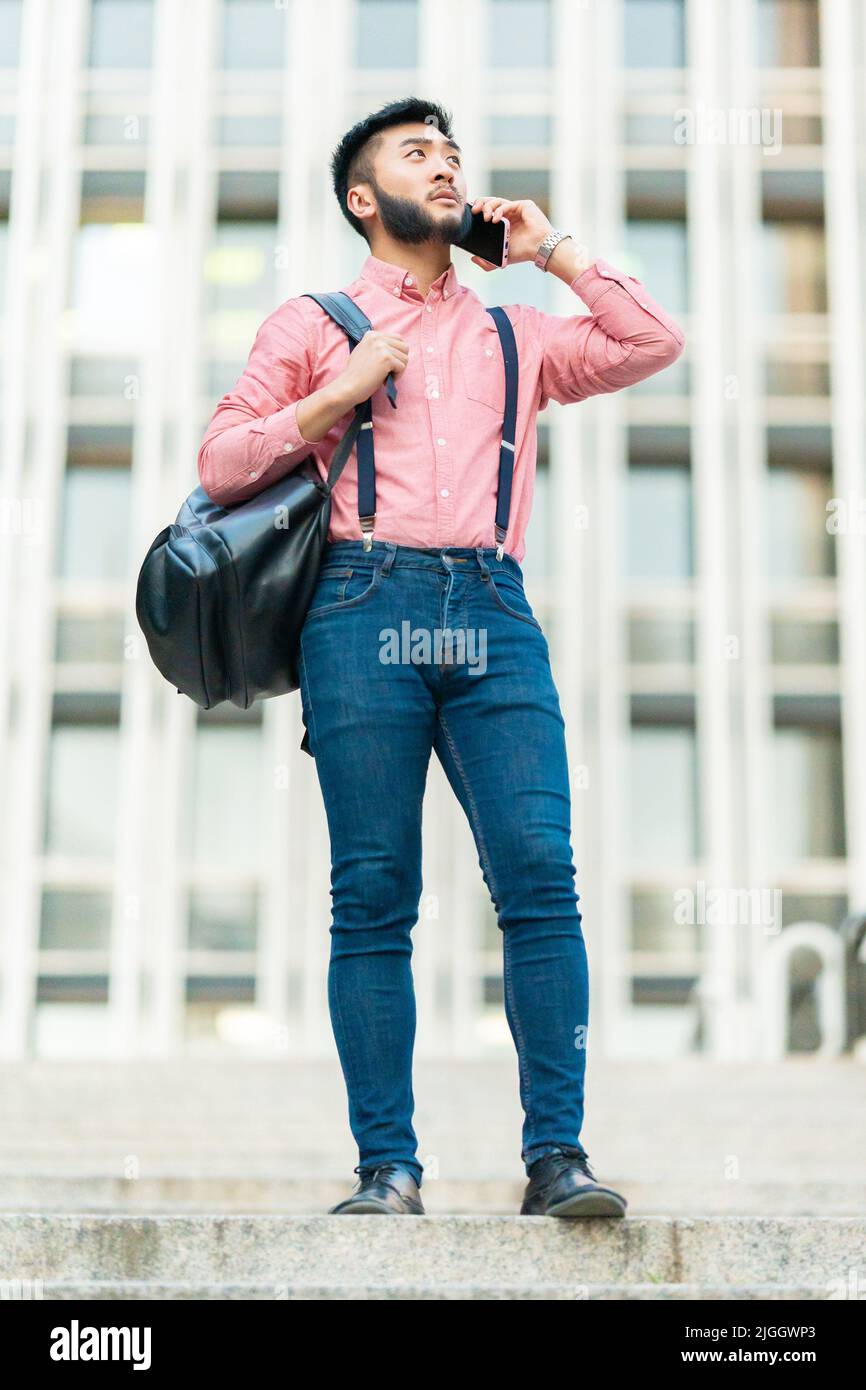 Asiatischer Mann mit lässiger Kleidung im Gespräch mit dem Handy Stockfoto