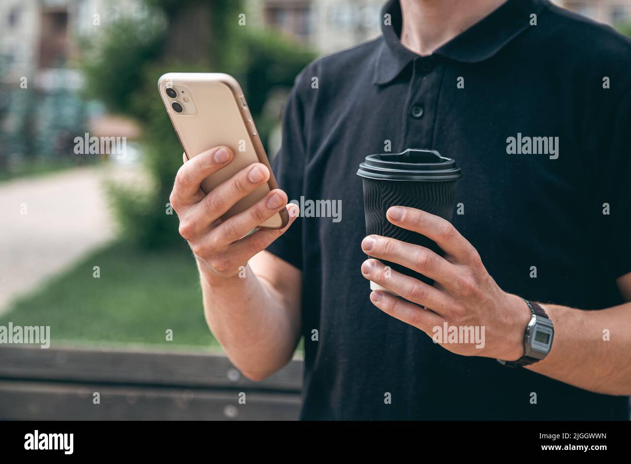 Nahaufnahme, Smartphone und ein Glas Kaffee in den Händen eines Mannes. Stockfoto