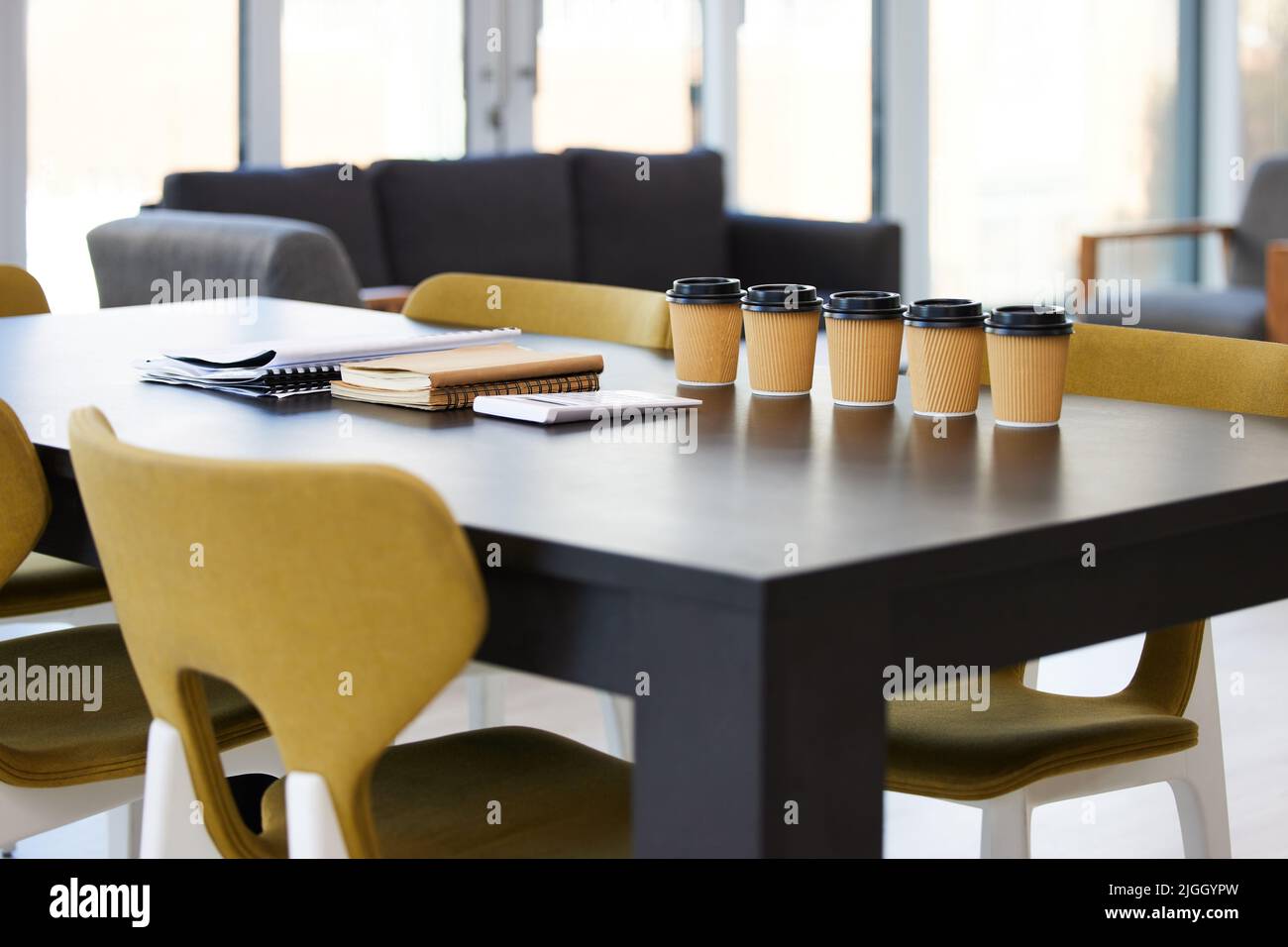 Bereit für das Meeting. Kaffee und Papierkram auf einem Schreibtisch in einem leeren Büro während des Tages. Stockfoto