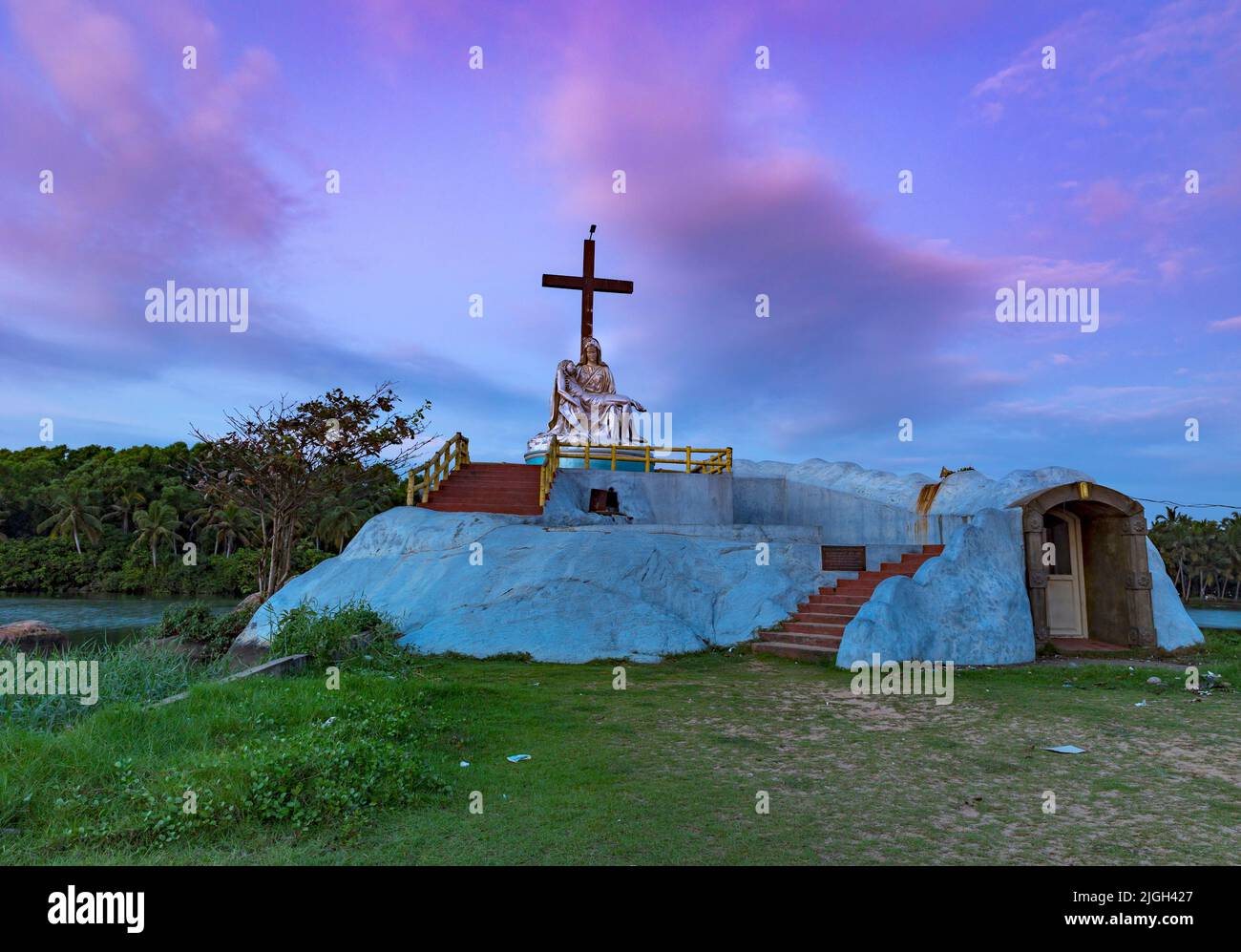Heilige Maria und Jesus Statue mit einem Kreuz im Poovar See, auf einem bunten Himmel Hintergrund. Thiruvananthapuram, Kerala, Indien. Stockfoto