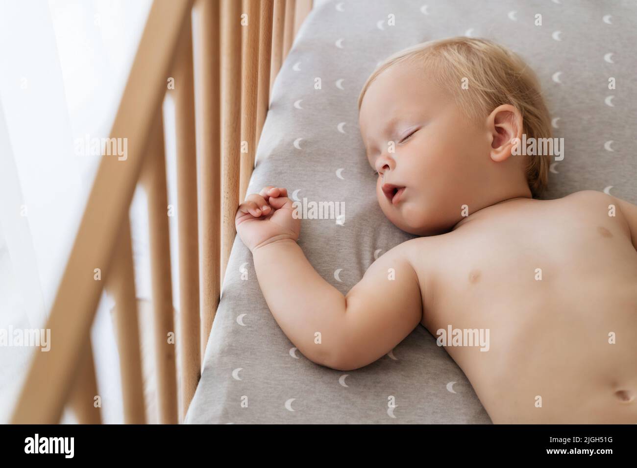 Nahaufnahme Porträt von niedlichen blonden kleinen Jungen mit weicher Haut schlafen in seinem Bett während der Mittagsschlaf Zeit in seinem Schlafzimmer. Sicherer, gesunder Schlaf. Konzept für die Kinderbetreuung Stockfoto