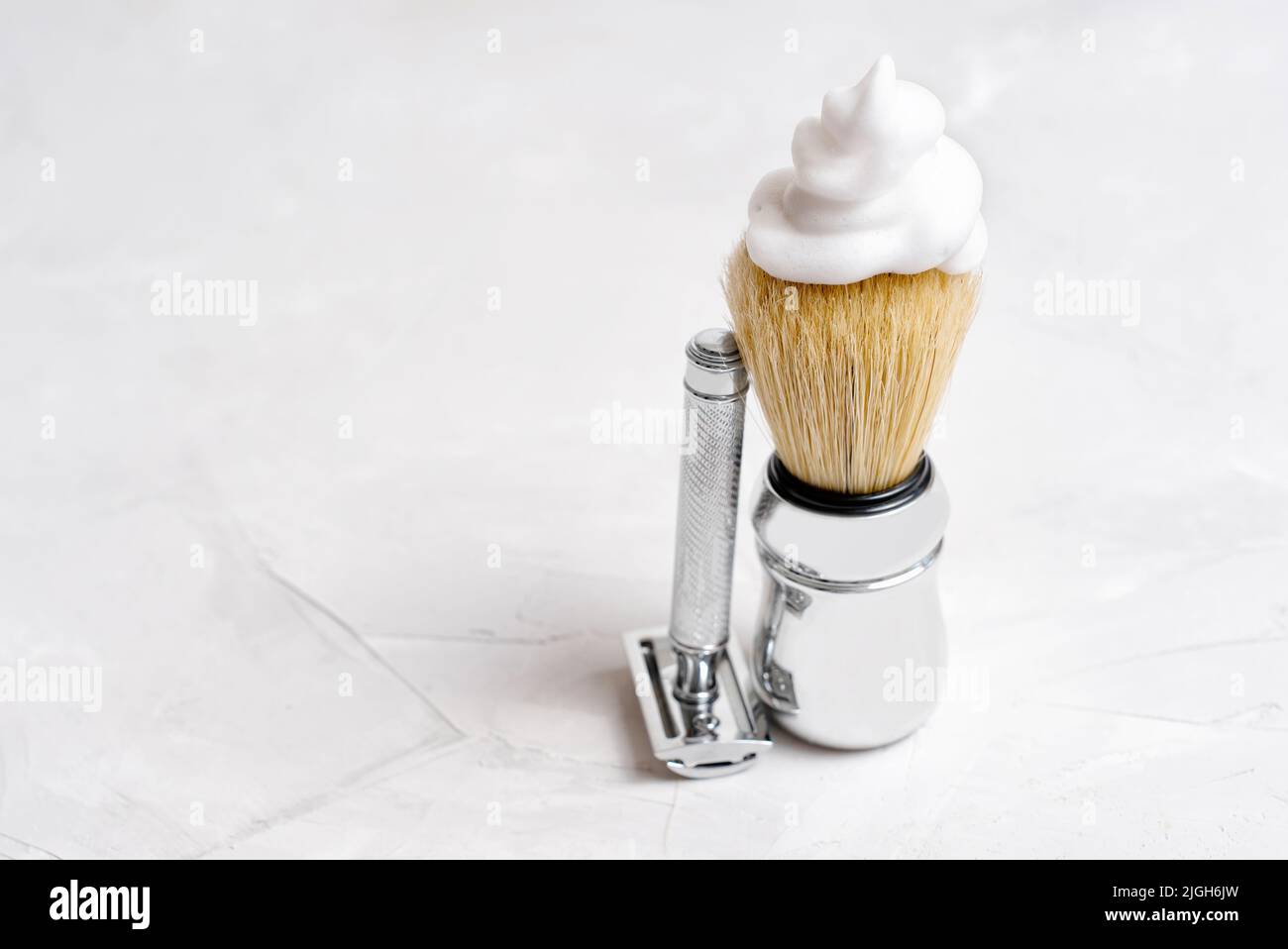 Sicherheitsrasierer und ein laderierter Rasierpinsel auf einem Betonhintergrund mit Kopierraum. Stockfoto