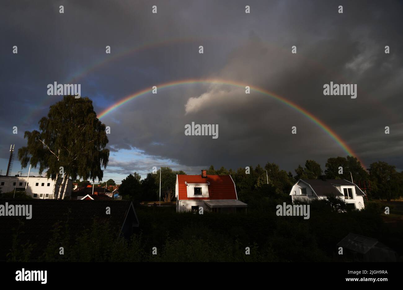 Motala, Schweden. 10., Juli 2022. Doppelter Regenbogen über der Stadt Motala, Schweden, während des Sonntagabends. Ein Regenbogen ist ein meteorologisches Phänomen, das durch Reflexion, Brechung und Ausbreitung von Licht in Wassertröpfchen verursacht wird, was zu einem Spektrum von Licht am Himmel führt. Quelle: Jeppe Gustafsson/Alamy Live News Stockfoto