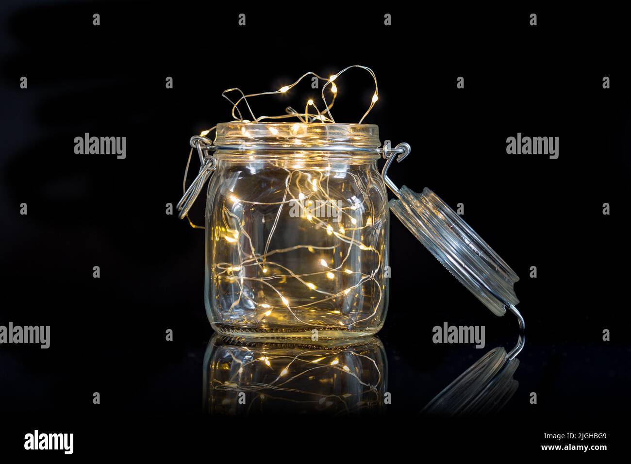 String Lichter in einem offenen Einmachglas isoliert auf schwarzem Hintergrund Stockfoto
