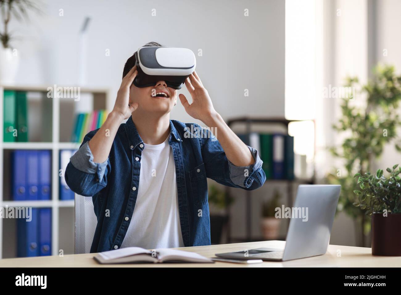 Freizeit Im Büro. Porträt eines aufgeregt jungen Mannes mit VR-Brille am Arbeitsplatz Stockfoto