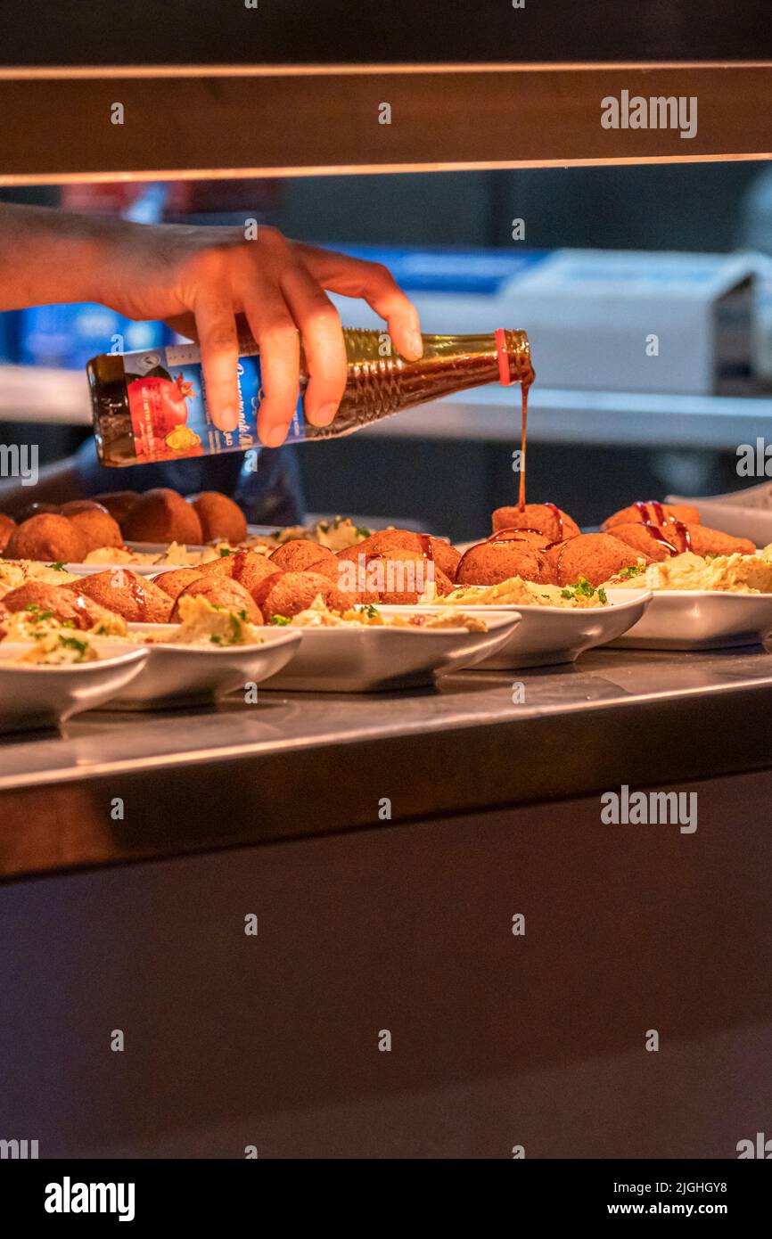 Granatapfel-Dressing zu den Gerichten der Speisen auf dem Pass hinzugefügt werden, die bei einem Nahost-Fest zur Unterstützung der Falmouth und Penryn Welcome Re serviert werden Stockfoto