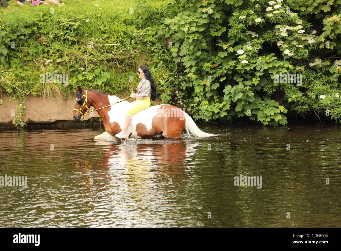 Eine junge Frau, die auf ihrem Pferd durch den Fluss Eden, Appleby Horse Fair und Appleby in Westmorland, Cumbria, reitet Stockfoto