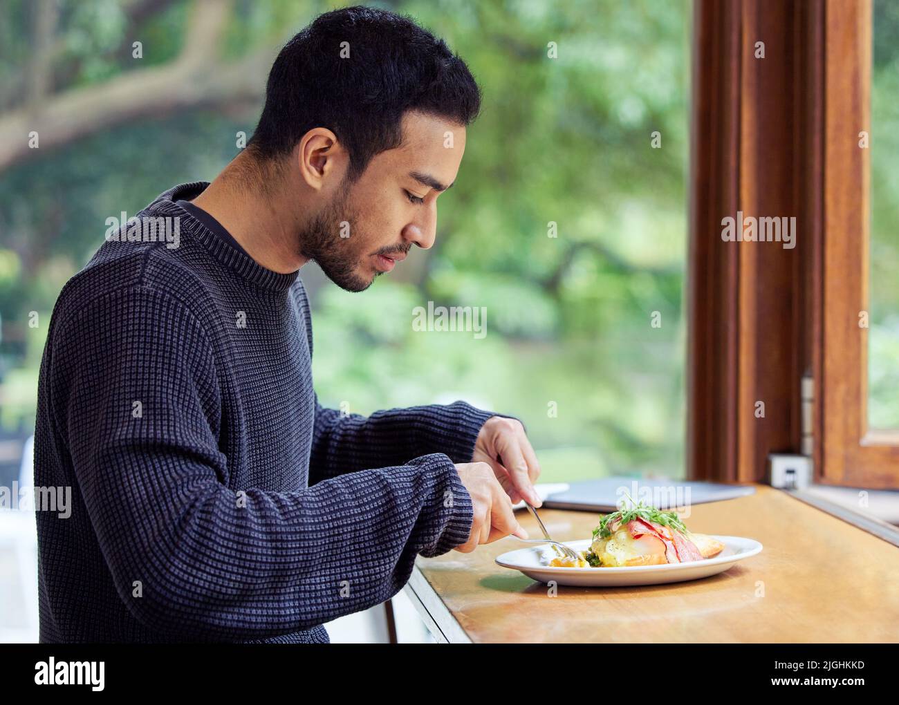Ich komme immer wieder hierher für das leckere Essen. Ein Mann genießt einen Teller Essen in einem Café. Stockfoto