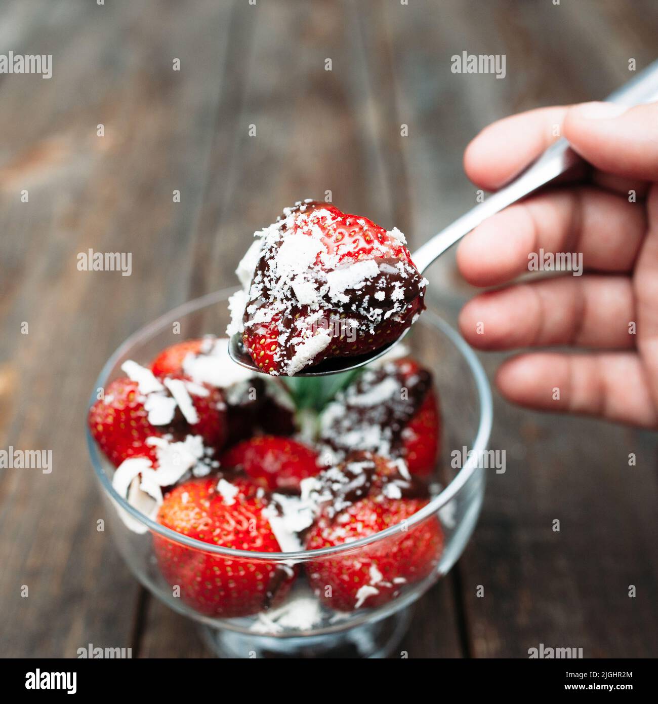 Erdbeere mit Schokolade essen, Holzkulisse Stockfoto
