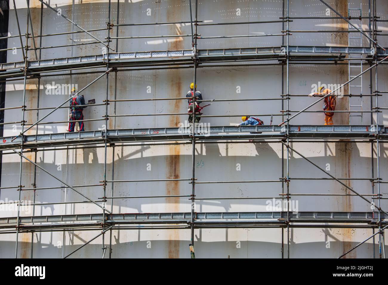 Bauarbeiter tanken Öl, indem sie Gerüste in der Raffinerie vor Ort installieren Stockfoto