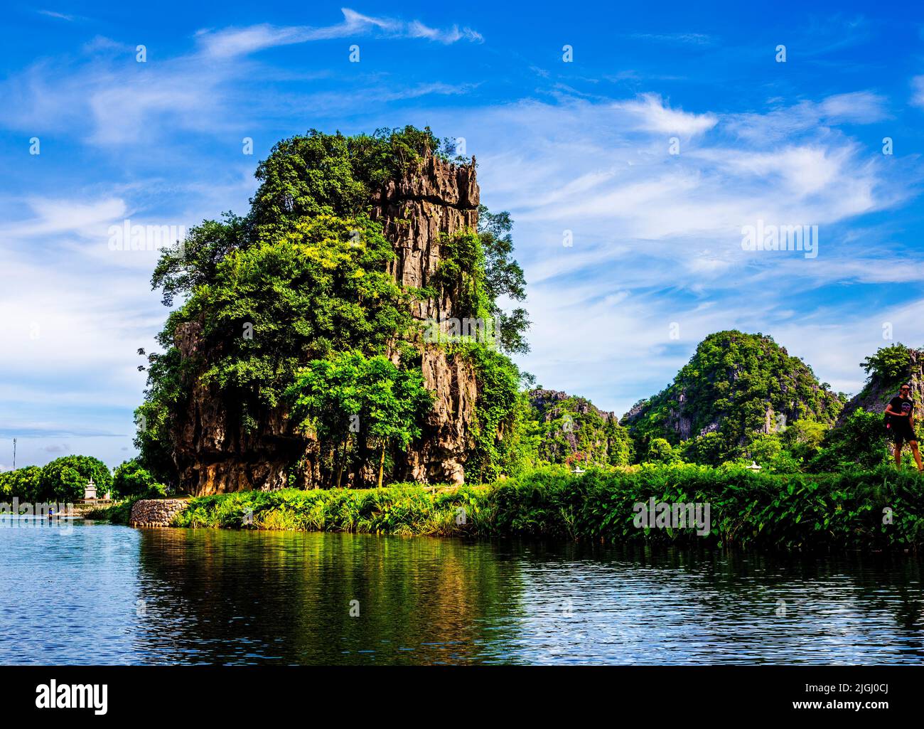 Kalksteinfelsen, umgeben von Wasser, blauem Himmel und grüner Dschungelvegetation, begeistern die Touristen. Stockfoto