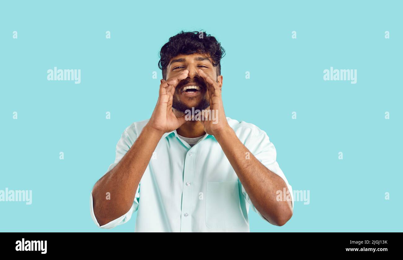 Studioportrait eines glücklichen jungen Indianers, der seine Hände am Mund hält und schreit Stockfoto