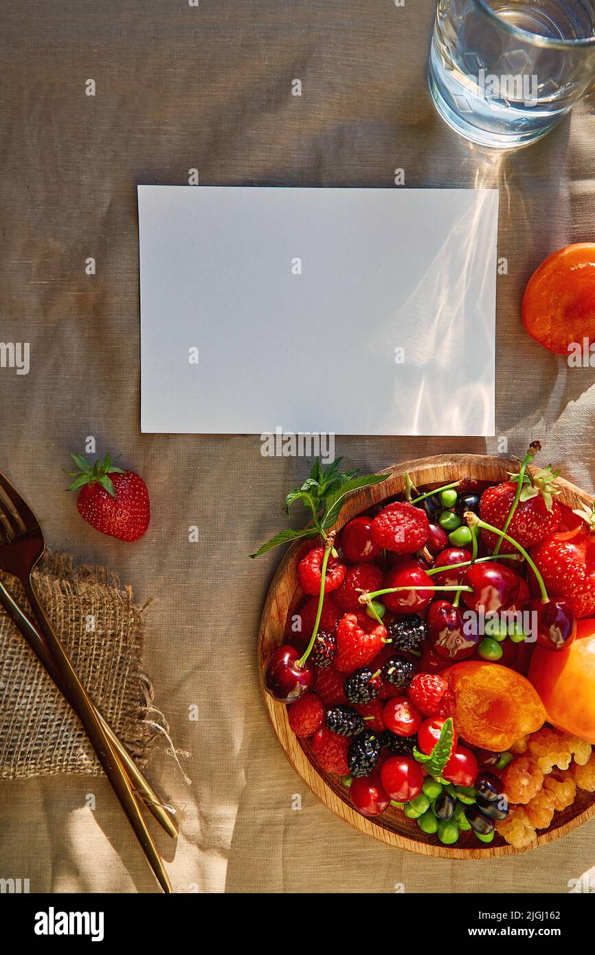 Rustikale, saisonale Schreibwaren-Karte mit harten Schatten, Sonnenlicht und frischen Früchten und Beeren. Draufsicht. Stockfoto