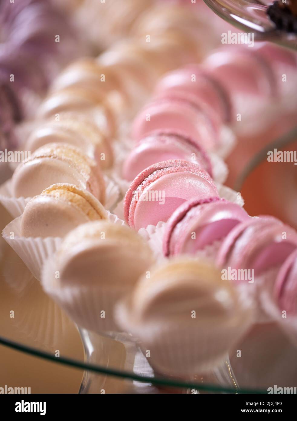 Frische, appetitliche, süße, rosafarbene, cremige und violette Makronen schließen sich an einem dekorierten festlichen Buffettisch an Stockfoto