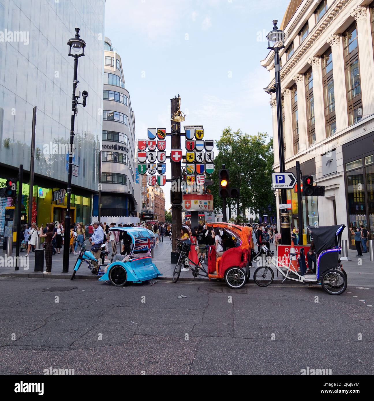 Rikschas aka Pedicabs aka Tuk-Tuks aka Bike Cab am Rande des Leicester Square, vor der Schweizer Kantonsplagge. London. Stockfoto