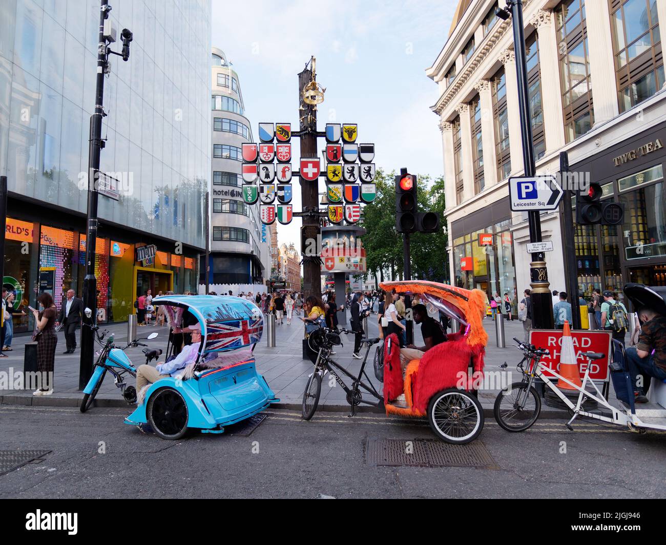 Rikschas aka Pedicabs aka Tuk-Tuks aka Bike Cab am Rande des Leicester Square, vor der Schweizer Kantonsplagge. London. Stockfoto