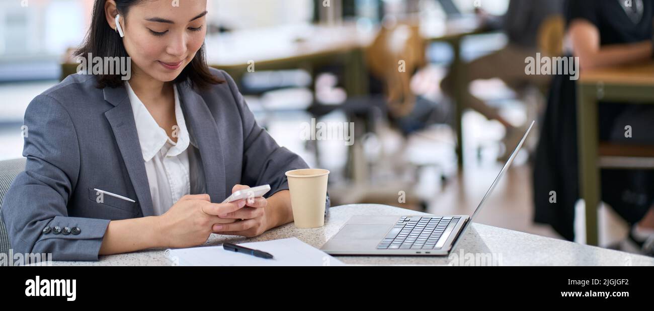 Junge asiatische Geschäftsfrau mit Smartphone bei der Arbeit. Banner Stockfoto