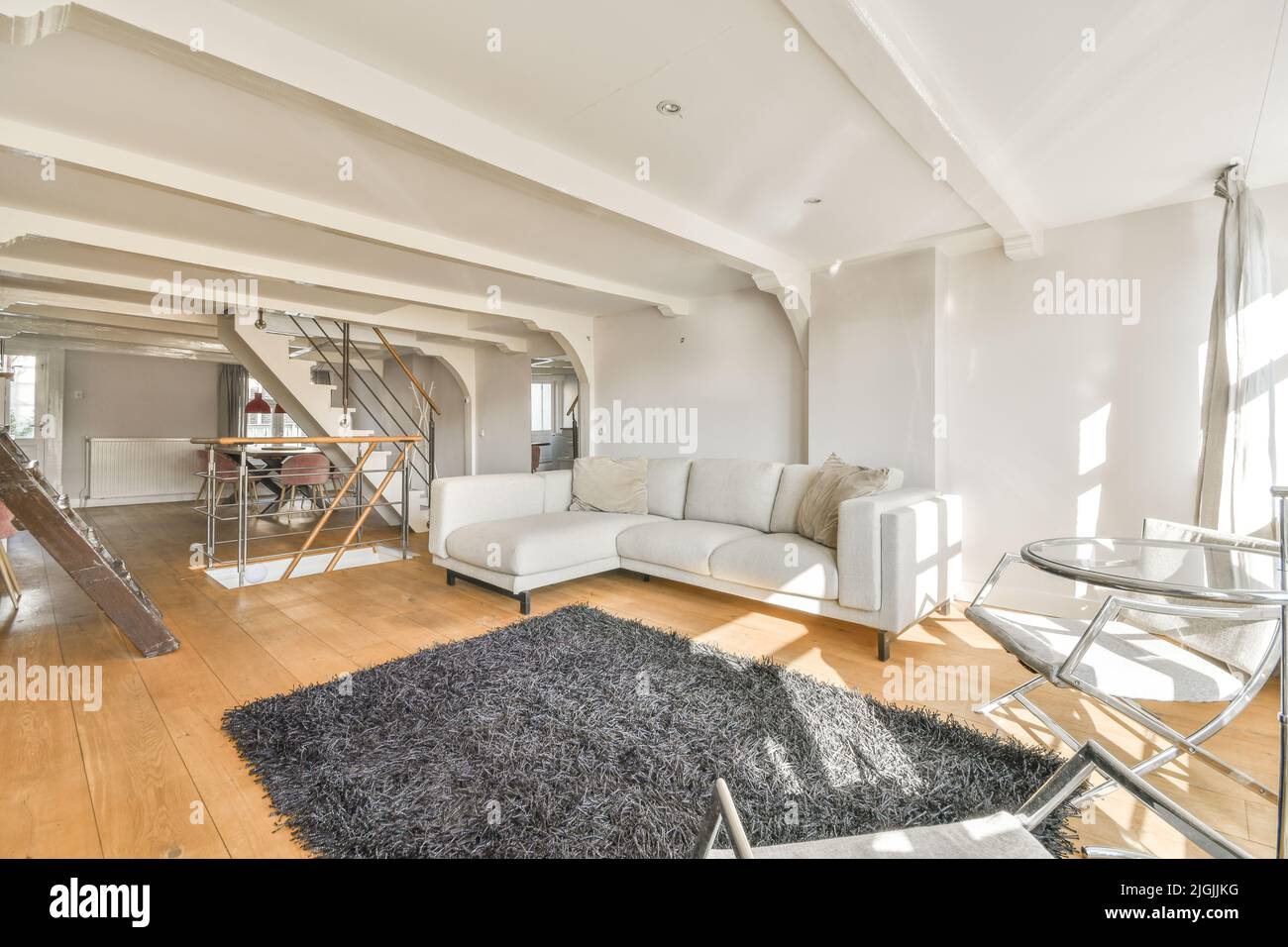 Tisch mit Stühlen und bequemes Sofa in einem geräumigen Zimmer mit stilvollen Dekorationen in modernen Wohnung befindet Stockfoto