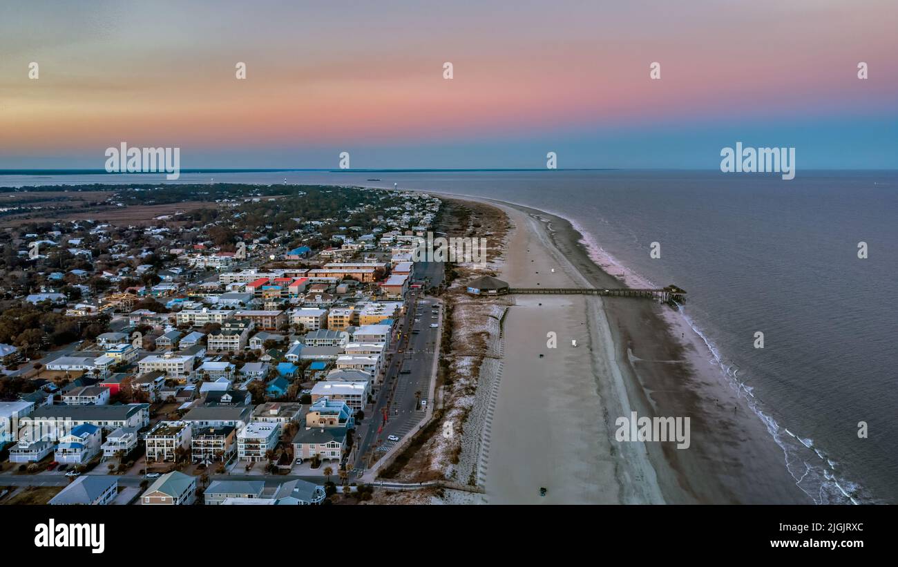 Luftdrohnenaufnahme von Tybee Island Beach und Pier in der Abenddämmerung, Richtung Norden. Farbenfroher Himmel mit leuchtenden Farben, der die ruhige Schönheit und Ruhe einfängt Stockfoto