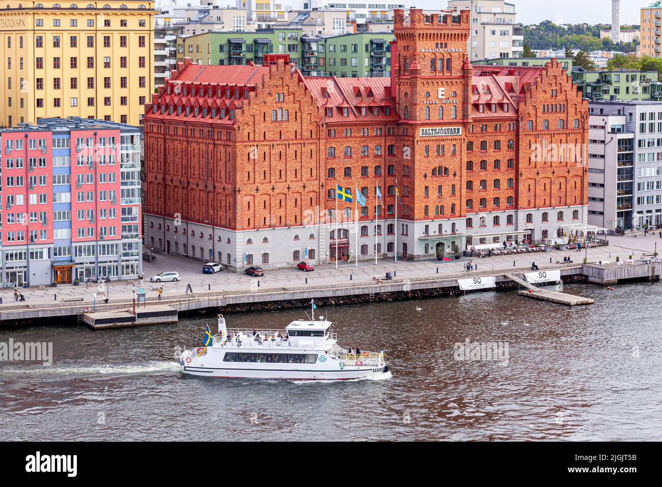 Die Fähre 'Clara' führt am Saltsjoqvarn-Gebäude (ursprünglich eine Mühle, jetzt aber Elite Hotel Marina Tower) in Danviken, Henriksdal im Stockholmer Archi vorbei Stockfoto