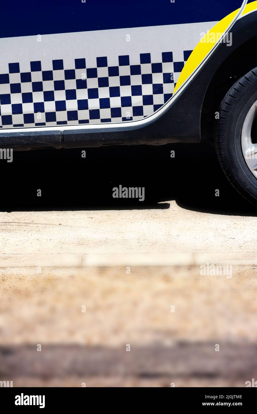 Detail des Abziehzeichens mit weißen und blauen Quadraten auf der Unterseite eines spanischen Polizeiautos. Vertikales Bild Stockfoto