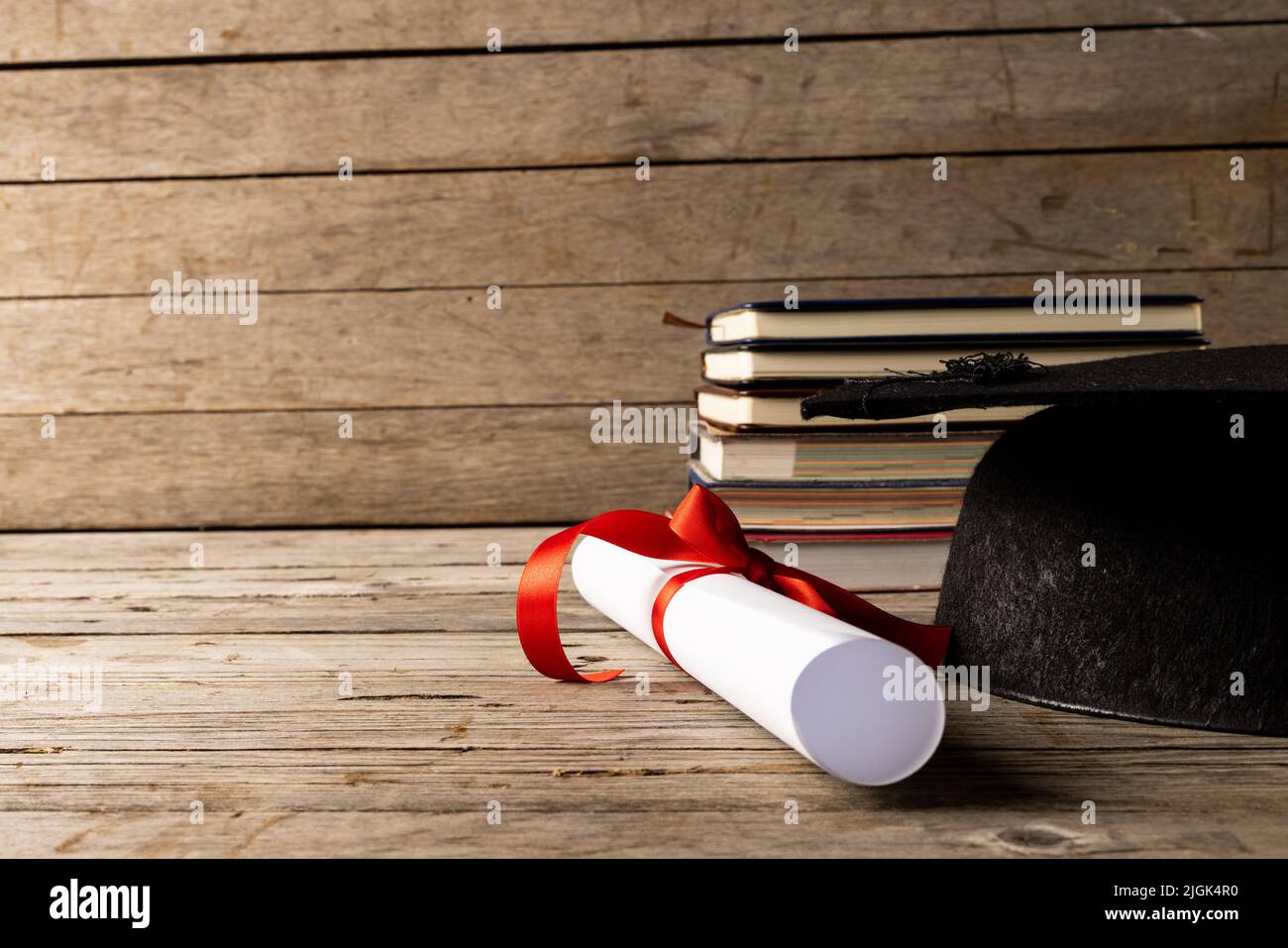 Das Bild des Stapels der Bücher und des Diploms auf der hölzernen Oberfläche Stockfoto