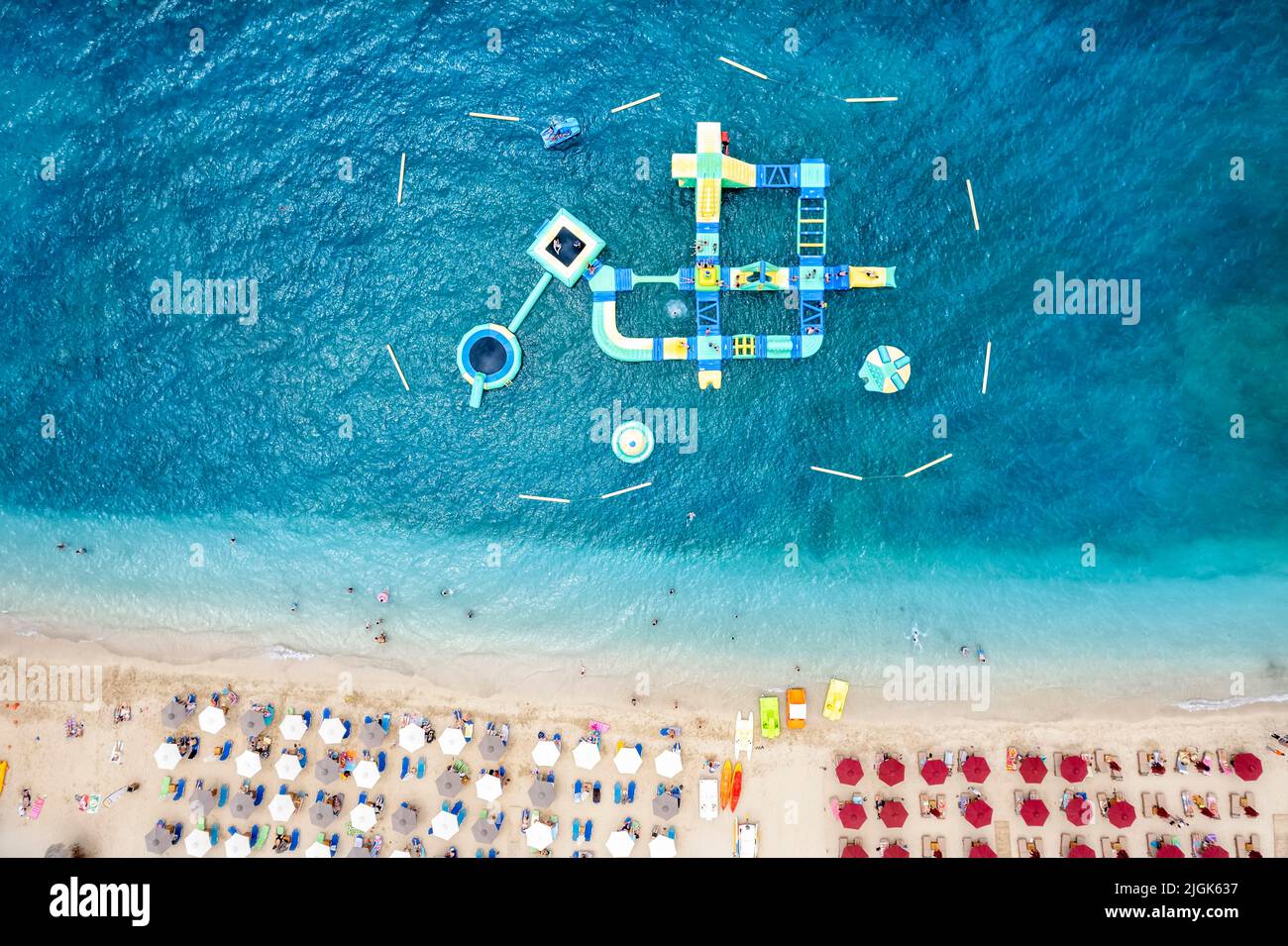 Blick von oben auf einen Strand mit türkisfarbenem Meer und einen schwimmenden Wasserpark Stockfoto