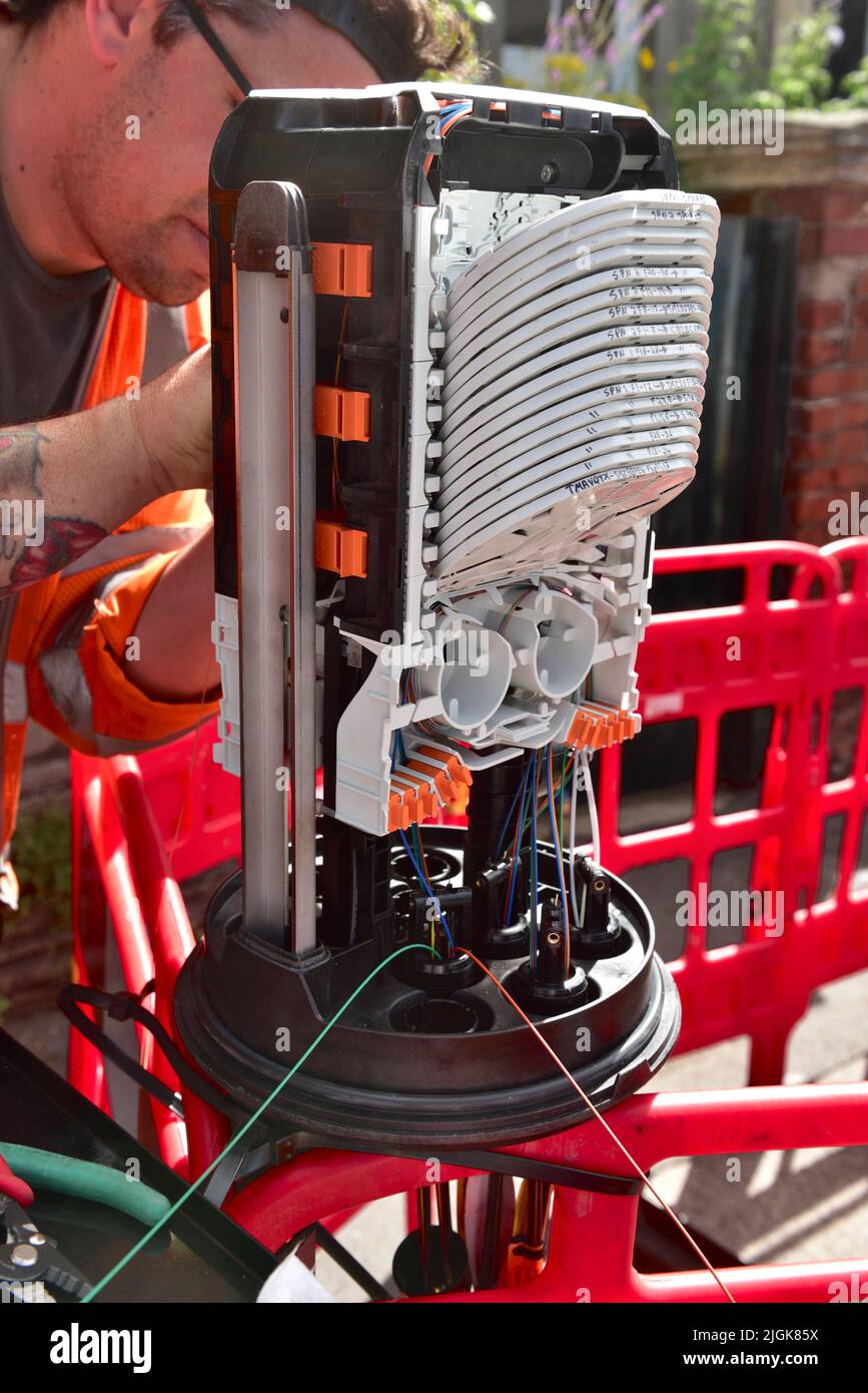 Ingenieur, der Glasfaser in einem Verteilzentrum für Glasfaserverkabelungen auf der Straße für Breitband und Telefon installiert, um letztendlich Glasfaser zu Hause zu erhalten Stockfoto