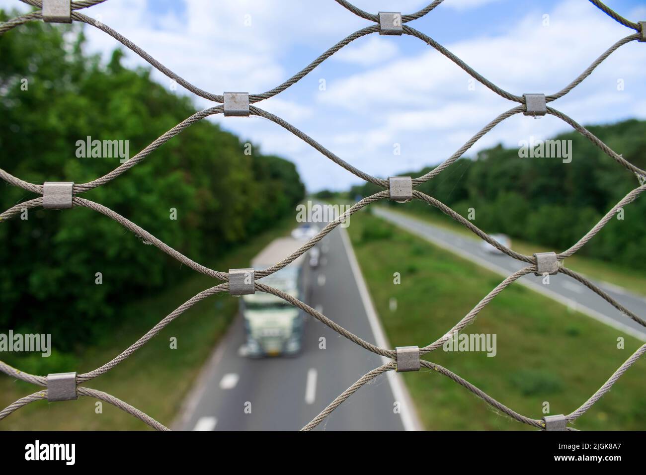 Schauen Sie durch ein Stahlgeflecht an der Seite der Fahrradbrücke Munlaan auf die Autobahn der Zukunft. Die Straße verbindet Oss City mit der Autobahn. Stockfoto