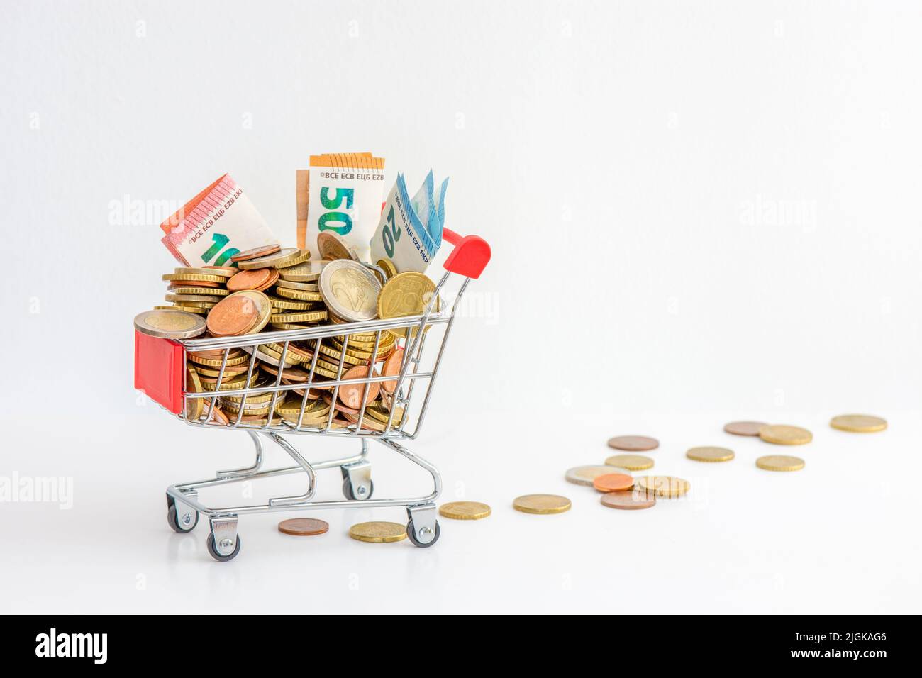Einkaufswagen überfüllt mit Bargeld (Euro-Münzen und Banknoten). Konzepte von steigenden Preisen, Kaufkraft und steigender Inflation in Europa Stockfoto