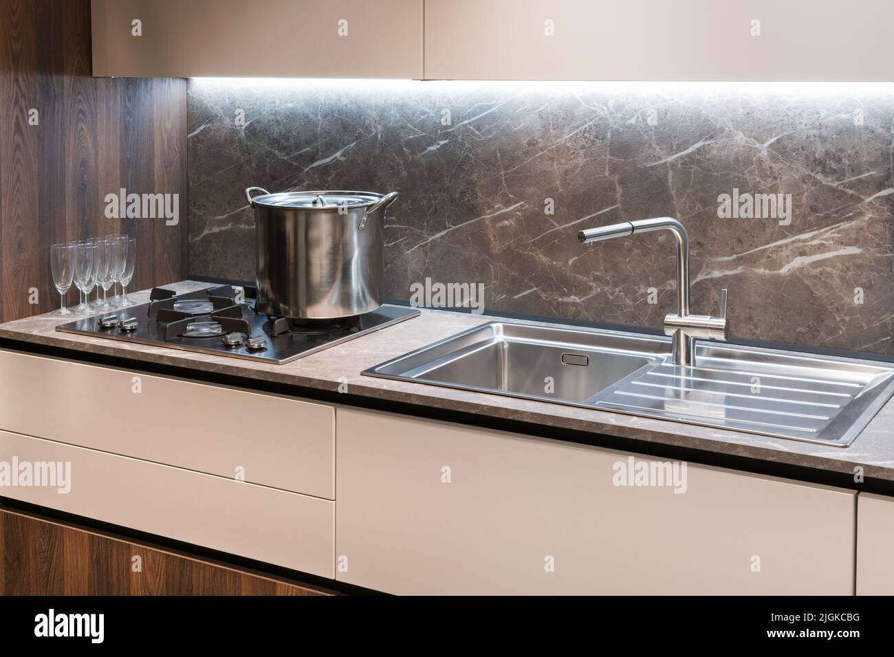 Gasherd mit Metallkochfeld und Waschbecken mit Wasserhahn auf Theken in der Nähe von Weinlaugen in der modernen Küche Stockfoto
