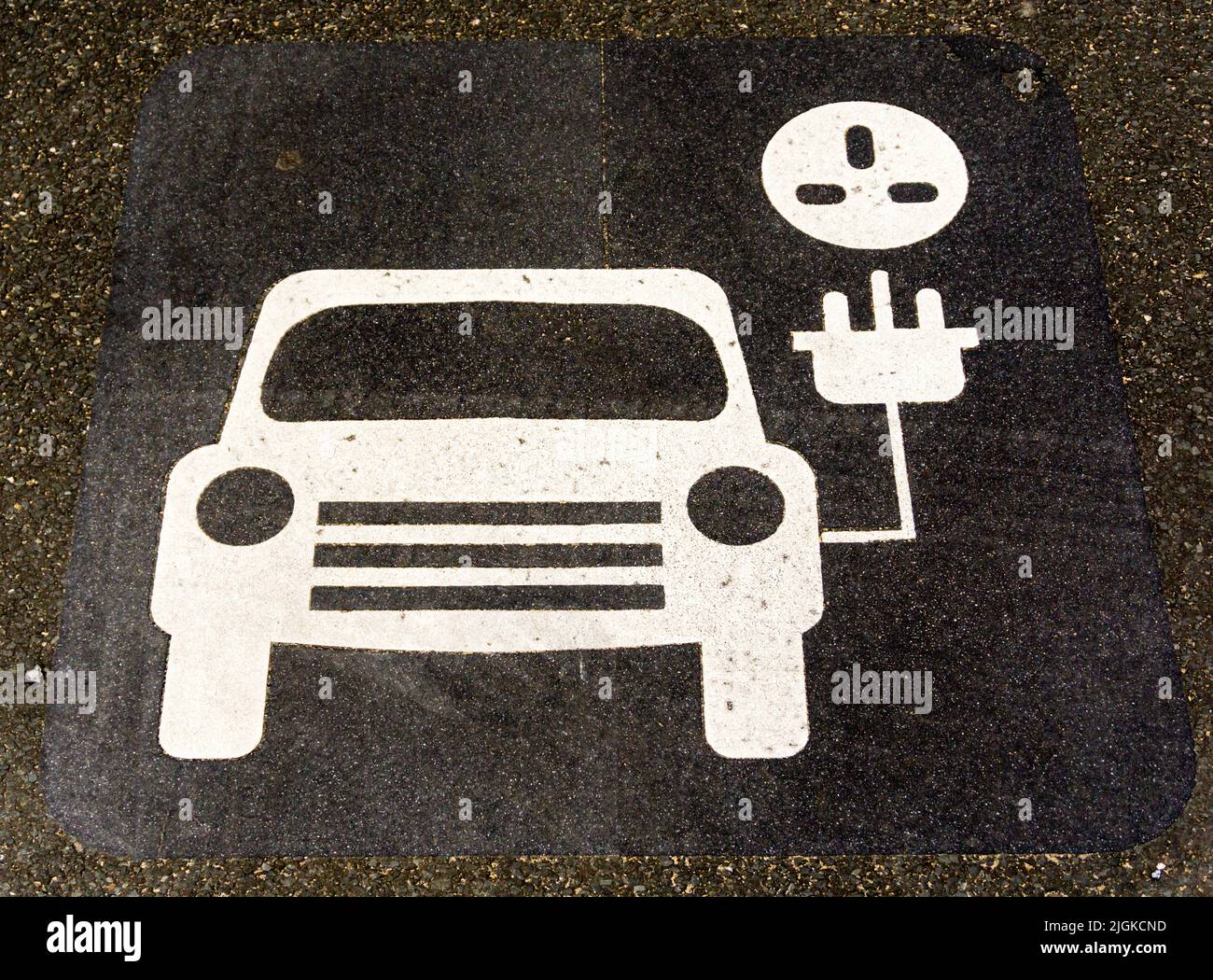 Schild auf Asphalt der Straße auf dem Parkplatz lackiert, um eine Ladestation für Elektrofahrzeuge zu zeigen. Stockfoto