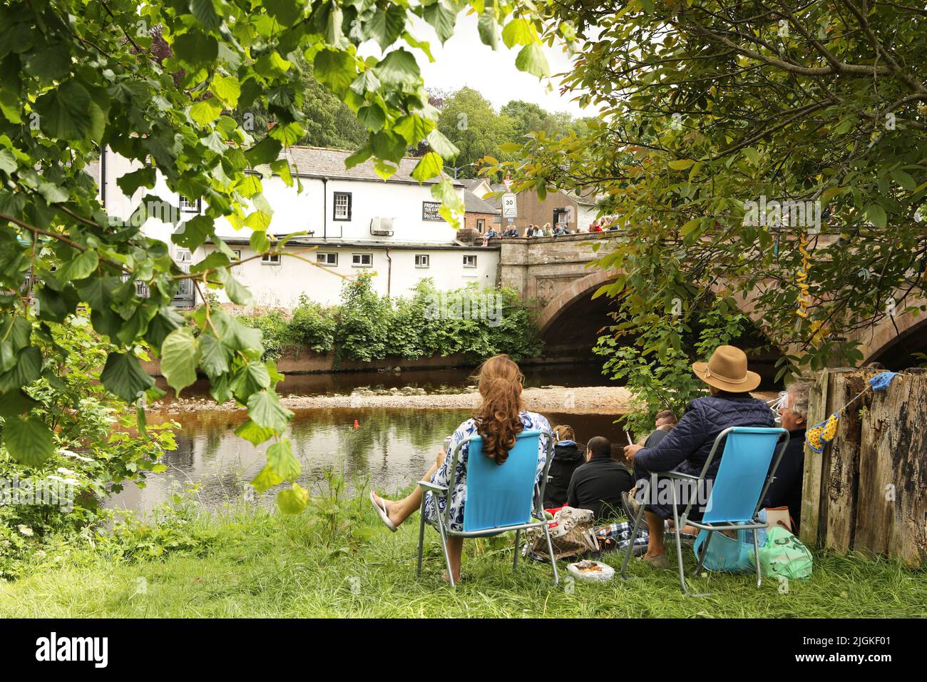 Ein Paar sitzt Liegestühle am Ufer des Flusses Eden, Appleby Horse Fair, Appleby in Westmorland, Cumbria Stockfoto