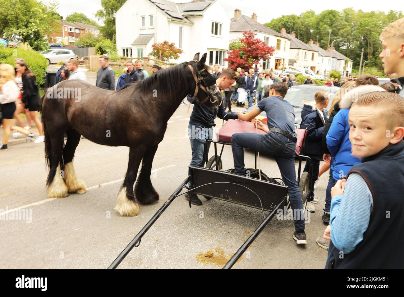 Zwei Jungen im Teenageralter, die ein schwarzes Pferd und eine Kutsche mit sich führen, Appleby Horse Fair, Appleby in Westmorland, Cumbria Stockfoto
